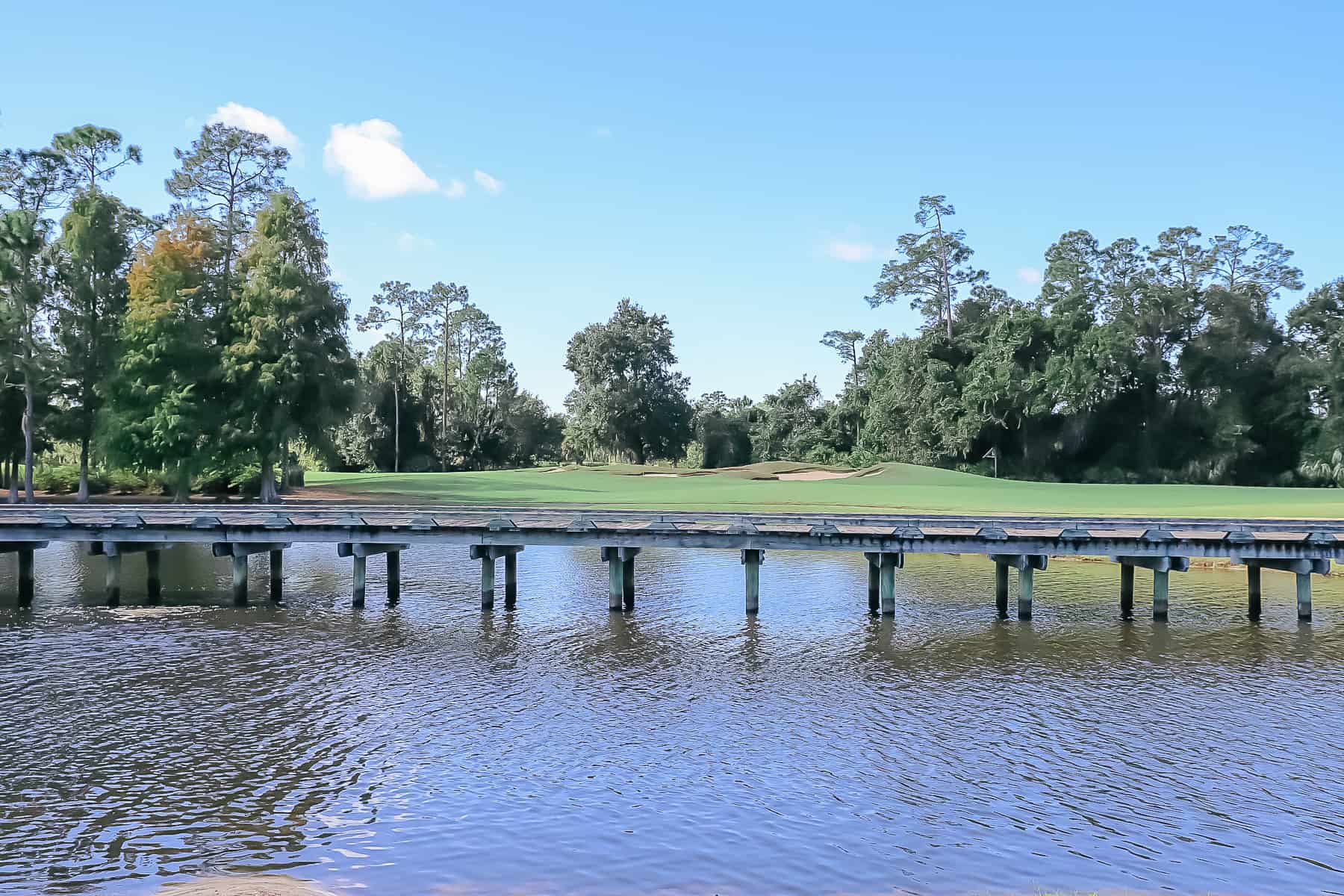 a golf cart bridge over the lake leading to the golf course 
