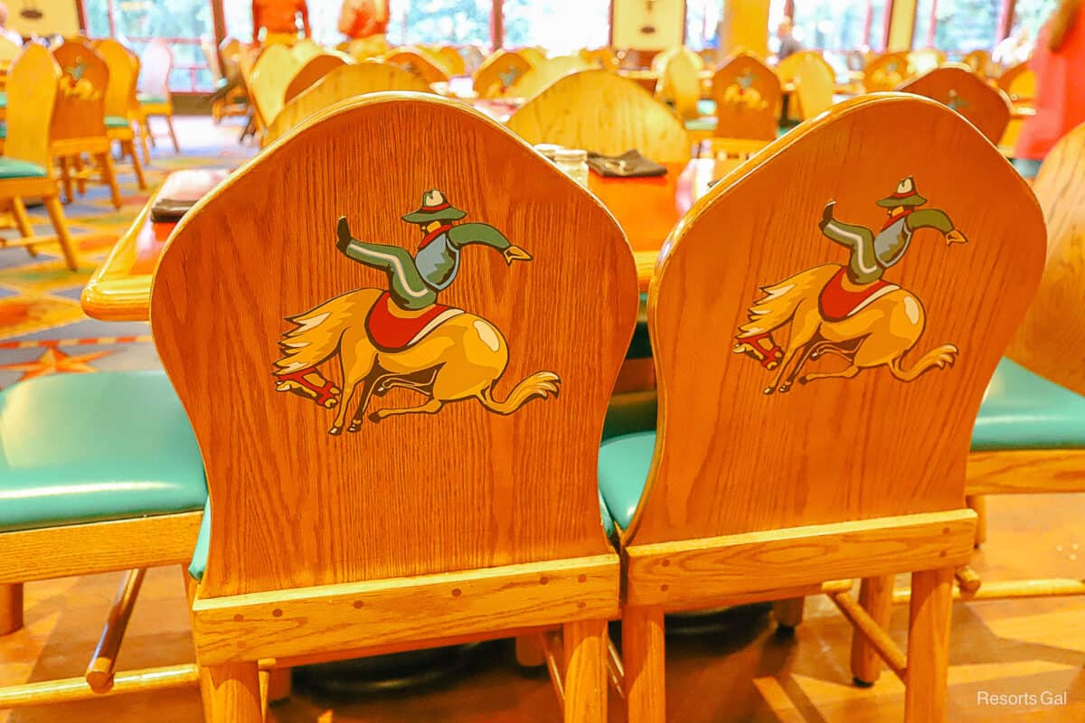 a close look at two chairs with a cowboy being thrown off a horse painted on the back 