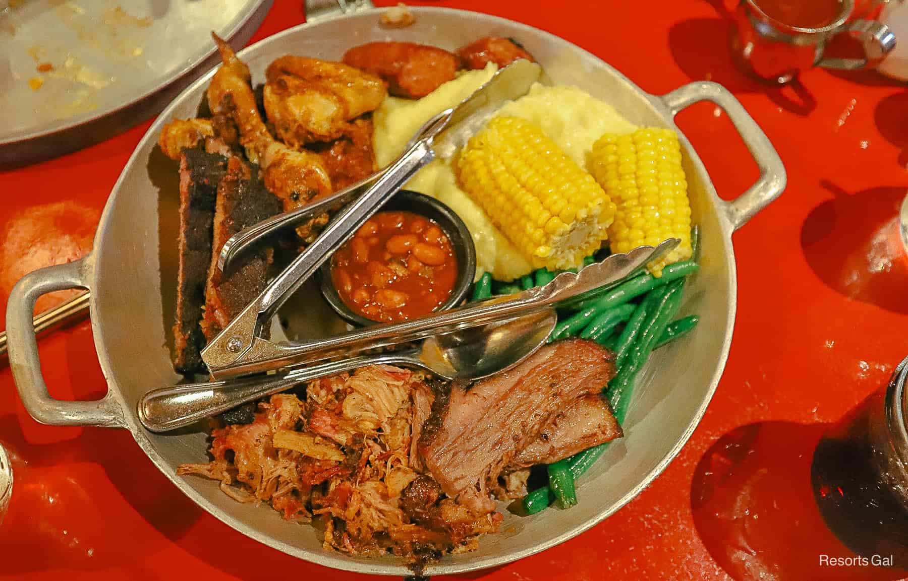 a skillet with Oak-smoked Beef Brisket, Pork Ribs, Slow-smoked Pulled Pork, Citrus-Herb Chicken, Western-style Sausage, Smashed Potatoes, Baked Beans, Buttered Corn on the Cob, Sautéed Green Beans (Price per person)
