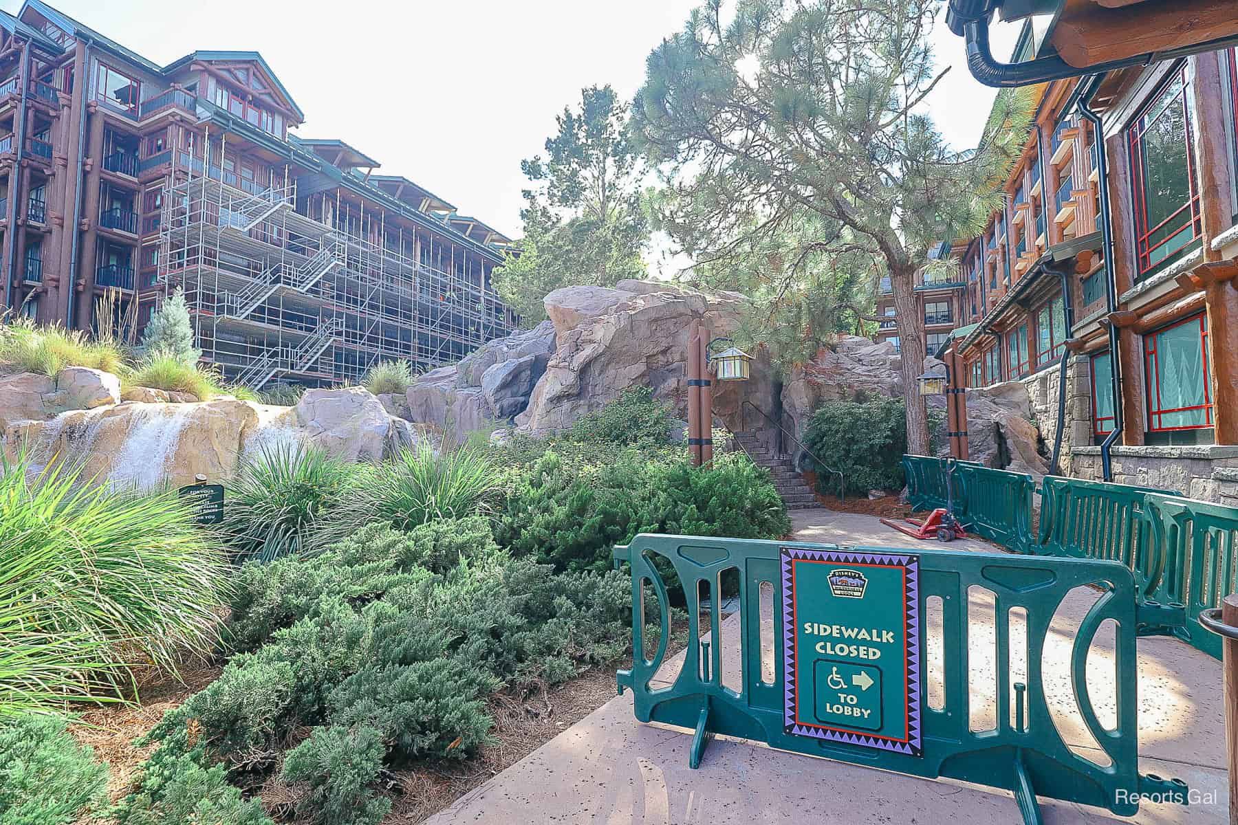 an exterior sign showing the sidewalk is closed with scaffolding surrounding the resort