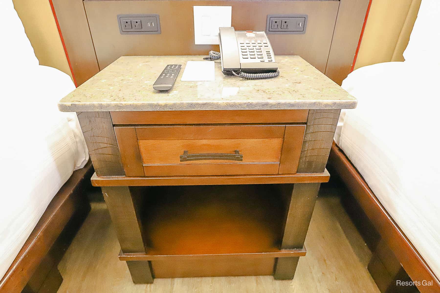 a night stand with a drawer between the two beds 