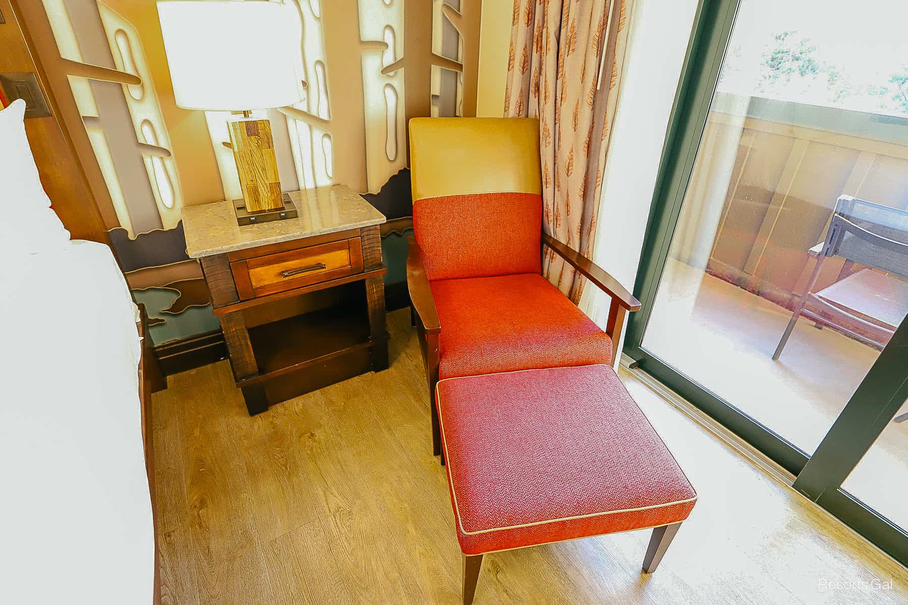 a close up of the red chair with foot stool trimmed in gold