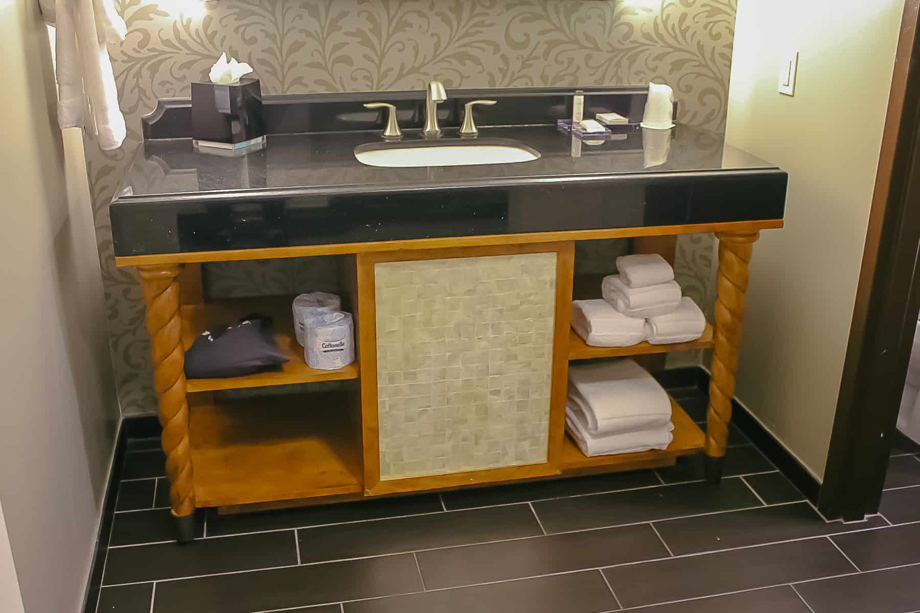 a vanity with one sink and open shelves underneath with a hairdryer and towels